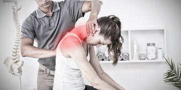 Therapeut wendet manuelle Therapie an der Schulter einer sitzenden Patientin an